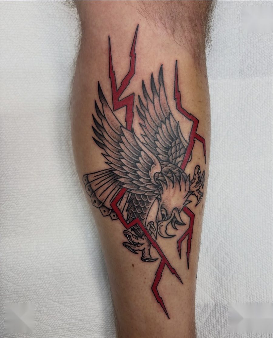 Traditional bald eagle with red lightning bolts tattooed on a calf by Tyson Sloan
